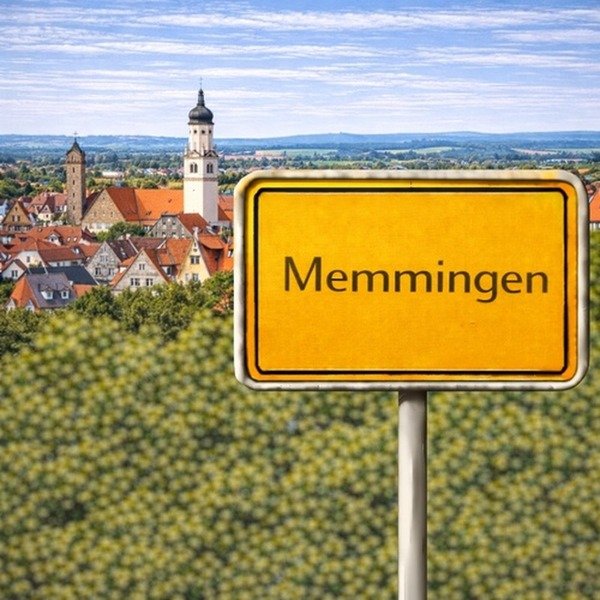 Gelbes Ortsschild Memmingen mit Stadt im Hintergrund